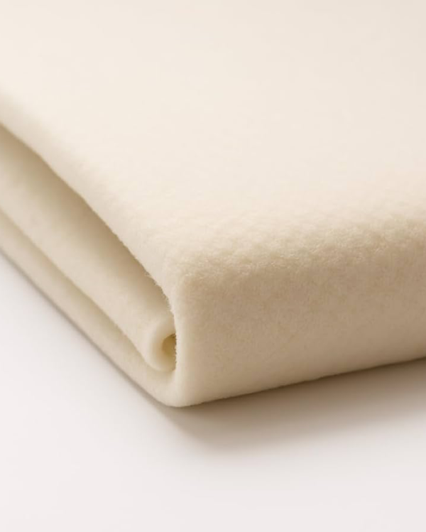 Close-up of folded beige fleece rug underlay showing thickness and soft texture